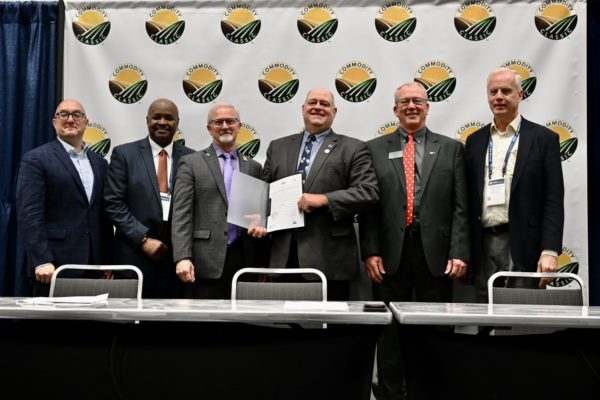 Six members of the checkoff partnership "Farmers for Soil Health" smile, holding the signed contract at the signing ceremony.