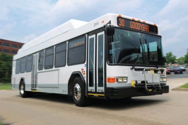 A white public transit bus drives in a parking lot.