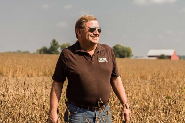 John Motter stands, smiling in a soy field.