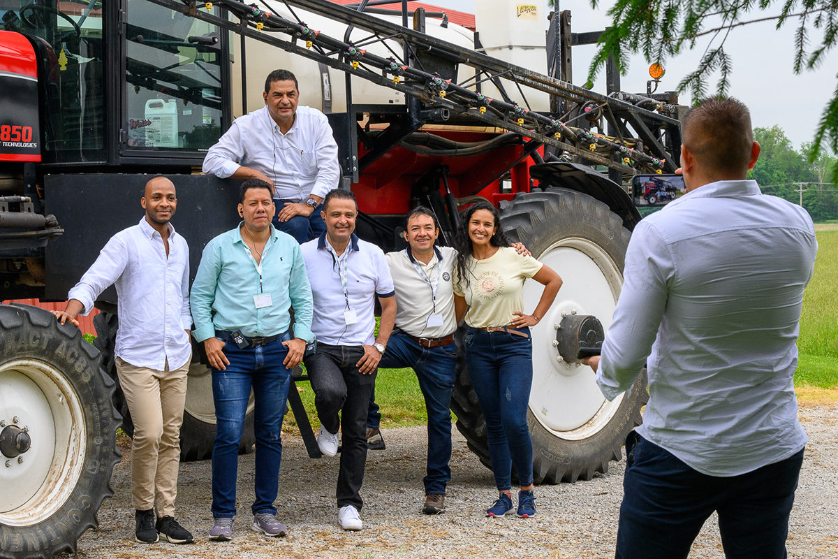 Chicago Board of Trade members pose for a photo in front of a red crop sprayer.
