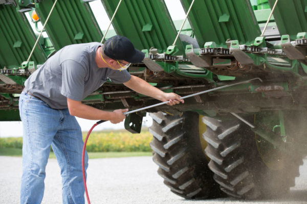 A farmer pressure washes his green seed planter to plant high oleic soybean seeds.