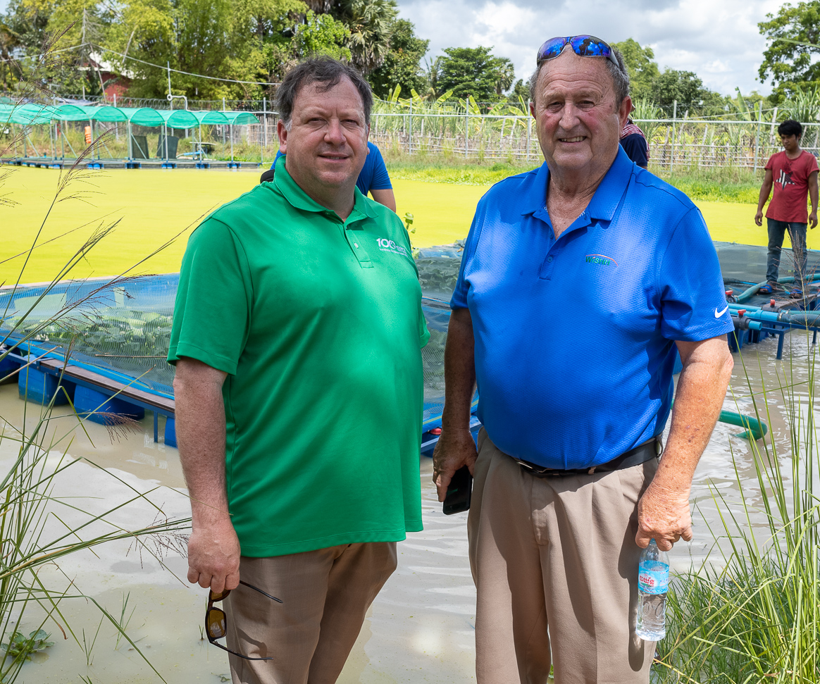 Two WISHH members stand in front of an aquaculture farm in Cambodia.