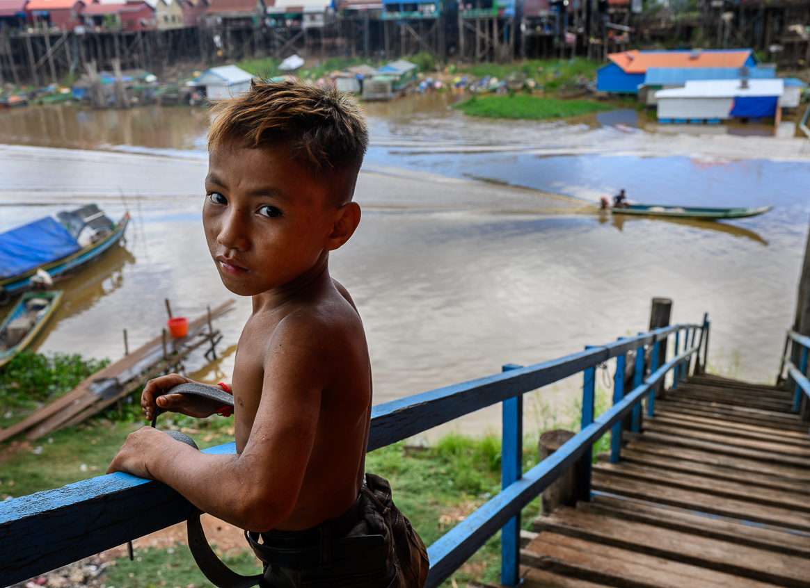 A Cambodian child stands on the stairs leading to a riverfront.