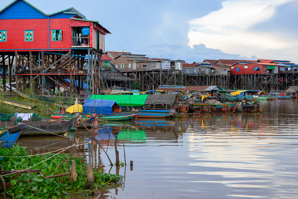 An array of raised colorful homes in Cambodia sit along the river.