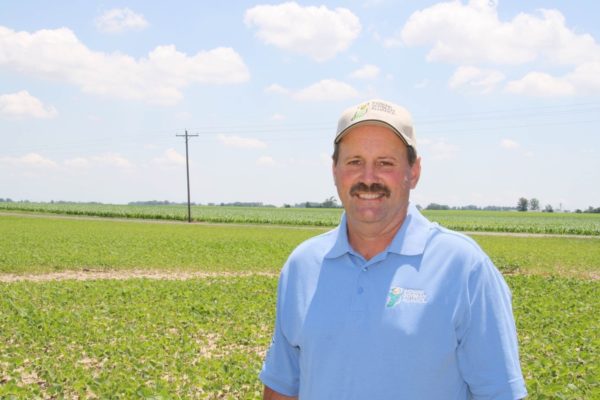Kevin Wilson smiles in front of open soy fields.