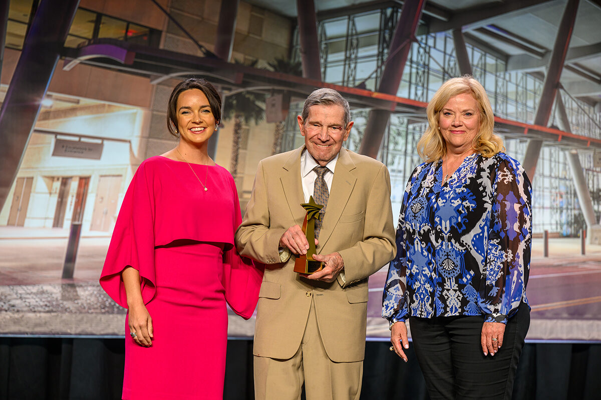 Kenneth Bader, Ph.D., holds the Tom Oswald Legacy Award while standing next to USB representatives Megan Kaiser and Susanne Oswald.
