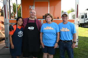 Four people smile for a picture at the Kansas City Barbecue competition.